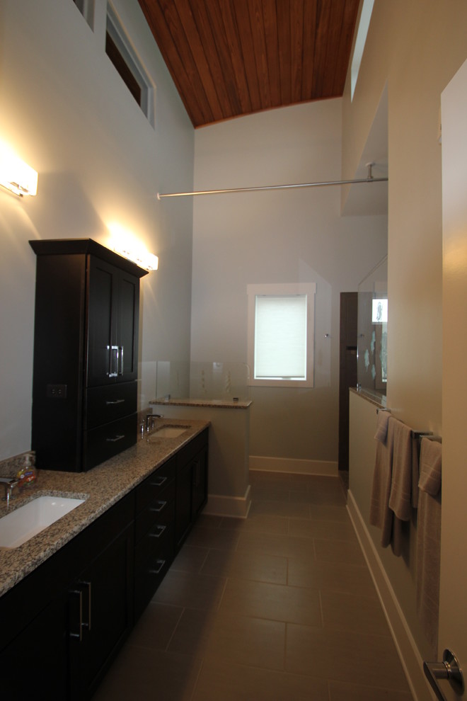 Walk-in shower - coastal gray tile and porcelain tile walk-in shower idea with an undermount sink, shaker cabinets, stainless steel cabinets, granite countertops and a two-piece toilet