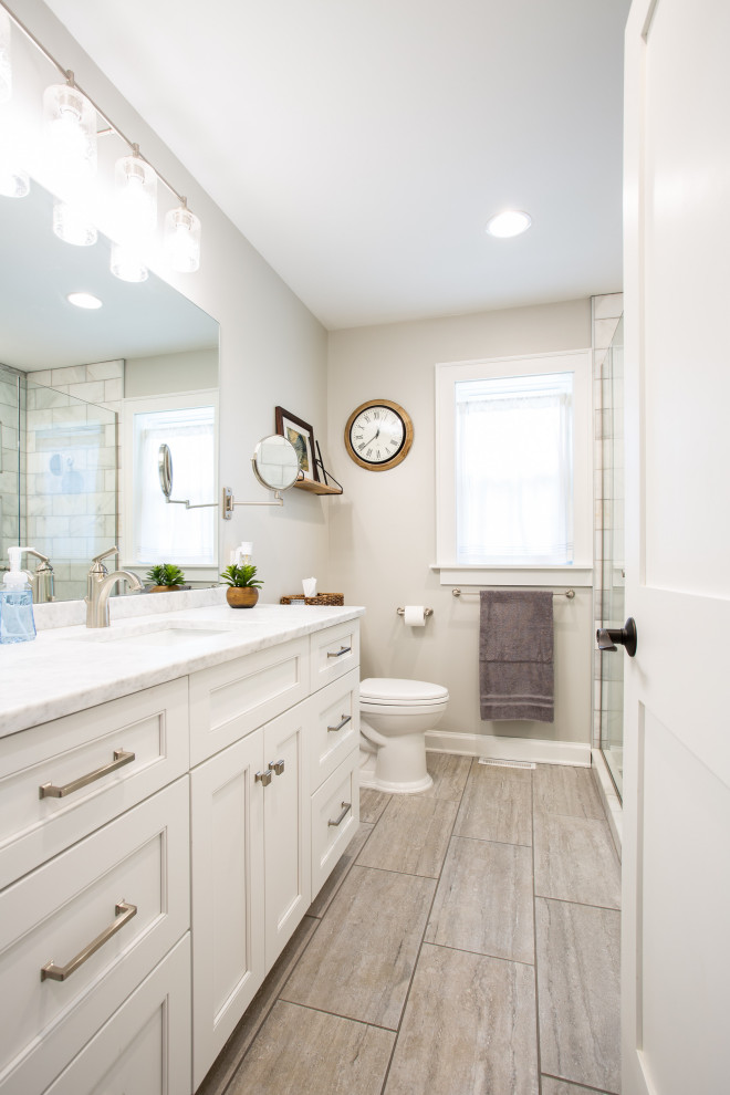 Example of a mid-sized classic master gray tile and stone tile ceramic tile, gray floor and single-sink alcove shower design in Columbus with shaker cabinets, white cabinets, a two-piece toilet, gray walls, an undermount sink, marble countertops, a hinged shower door, white countertops and a built-in vanity