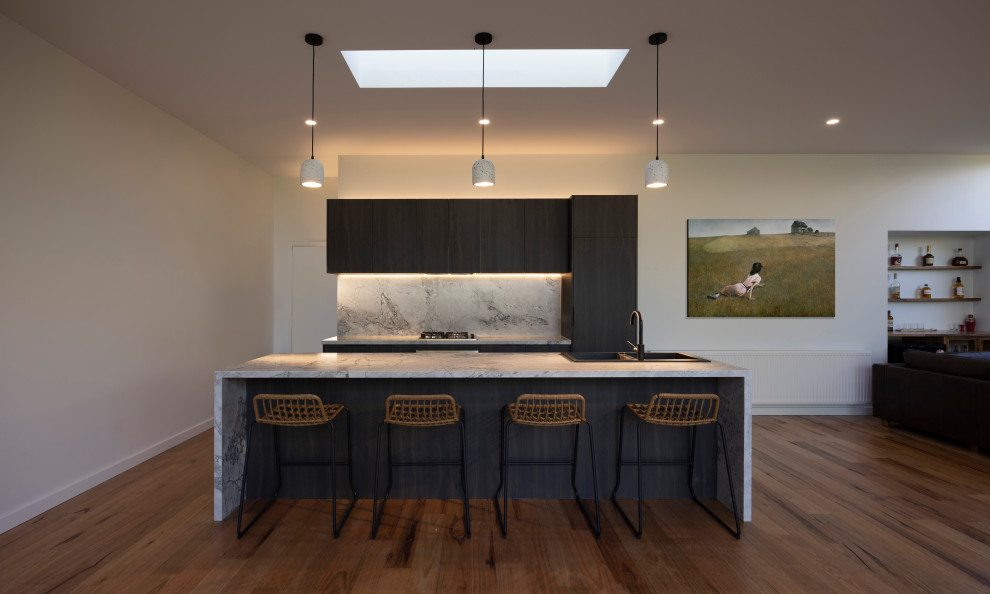 Large trendy single-wall light wood floor and brown floor open concept kitchen photo in Melbourne with flat-panel cabinets, brown cabinets, marble countertops, gray backsplash, marble backsplash, stainless steel appliances, an island and gray countertops