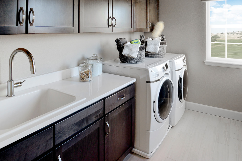 Photo of a transitional single-wall dedicated laundry room in Denver with brown cabinets, grey walls, a side-by-side washer and dryer and white benchtop.