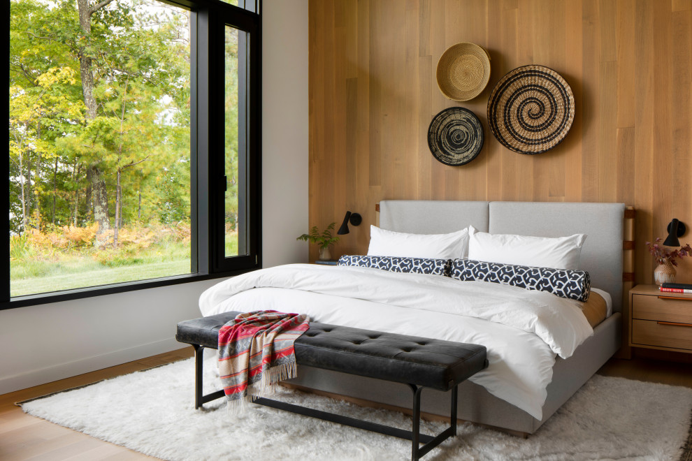 Example of a large trendy guest light wood floor, brown floor and wood wall bedroom design in Other with white walls