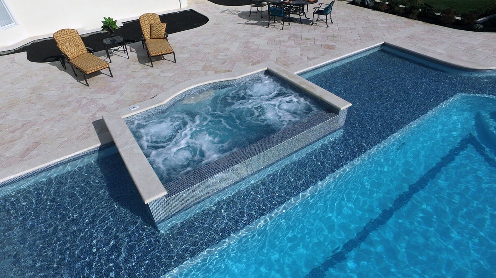 Example of a large backyard stone and custom-shaped lap hot tub design in New York