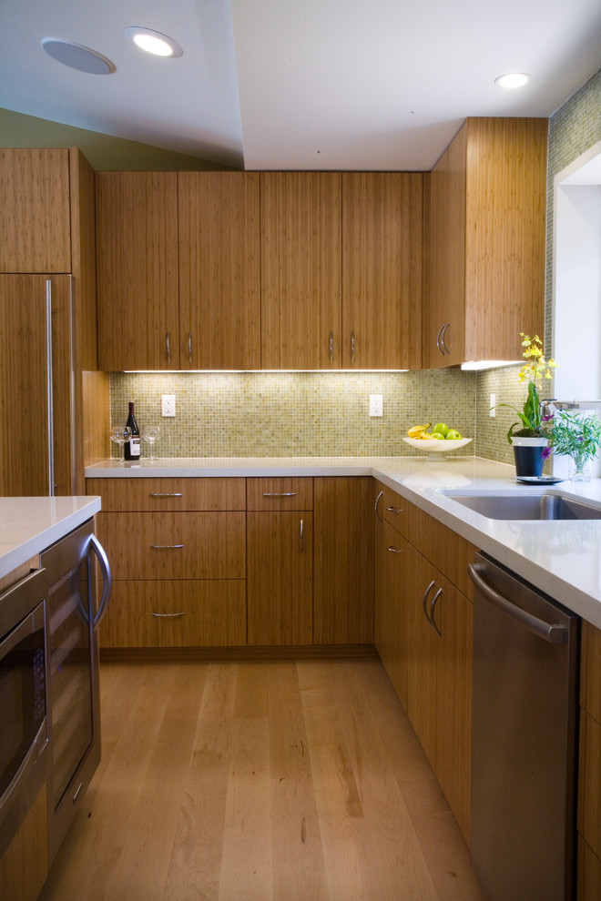 This is an example of a mid-sized midcentury u-shaped kitchen in San Francisco with an undermount sink, flat-panel cabinets, medium wood cabinets, stainless steel appliances, quartzite benchtops, beige splashback, glass tile splashback, light hardwood floors, with island, beige floor and white benchtop.