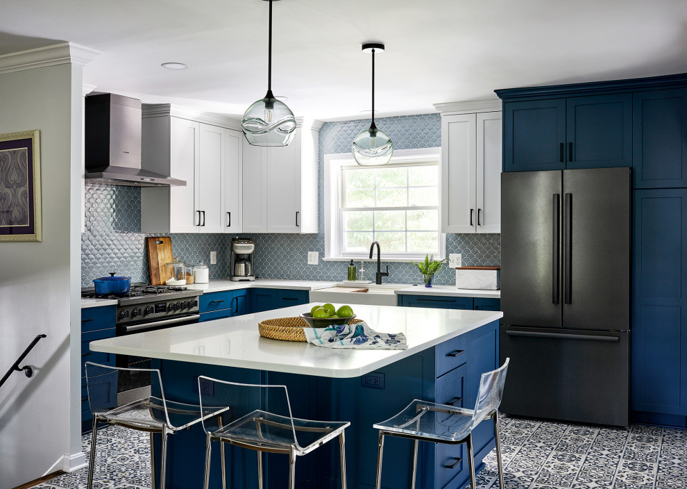Example of a transitional l-shaped blue floor eat-in kitchen design in DC Metro with a farmhouse sink, blue cabinets, blue backsplash, black appliances, an island and white countertops