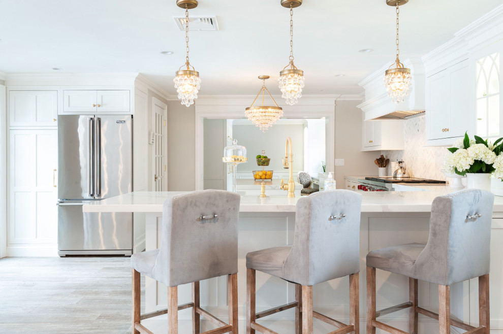 Large transitional l-shaped eat-in kitchen in New York with an undermount sink, shaker cabinets, white cabinets, quartzite benchtops, white splashback, mosaic tile splashback, stainless steel appliances, porcelain floors, with island, beige floor and white benchtop.