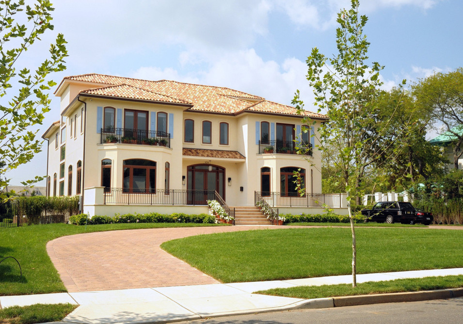 Expansive mediterranean two-storey stucco white house exterior in New York with a hip roof and a shingle roof.