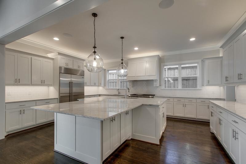 Photo of a large country u-shaped open plan kitchen in Dallas with a farmhouse sink, shaker cabinets, white cabinets, granite benchtops, white splashback, porcelain splashback, stainless steel appliances, medium hardwood floors and with island.