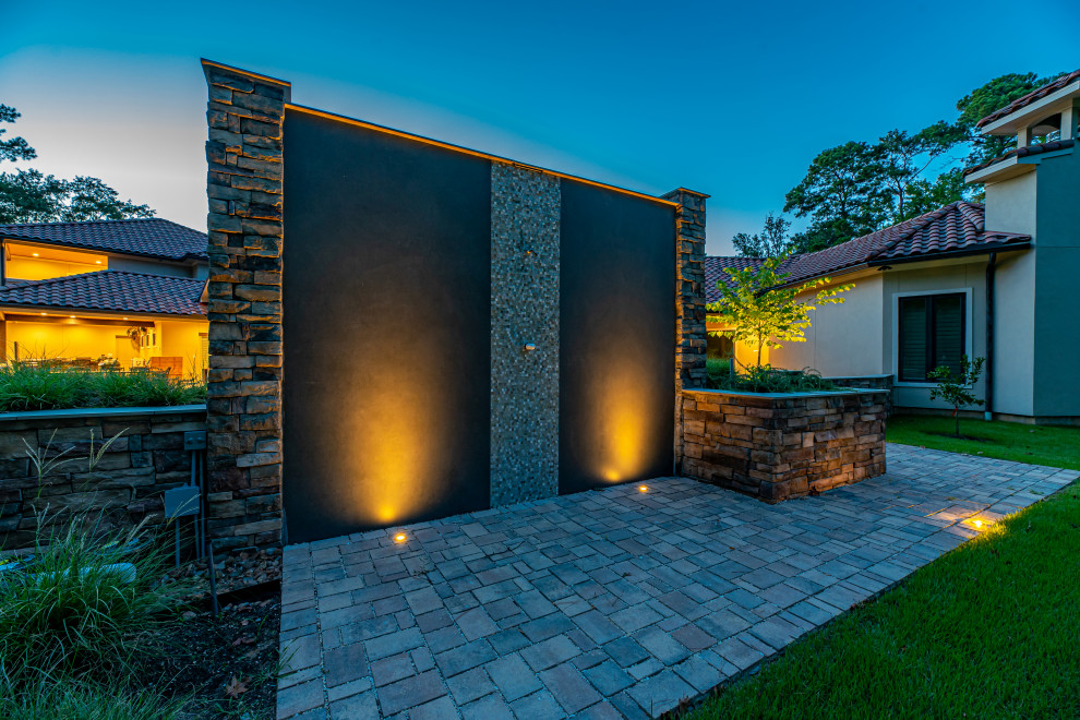 Foto di un'ampia piscina a sfioro infinito moderna personalizzata dietro casa con pavimentazioni in pietra naturale