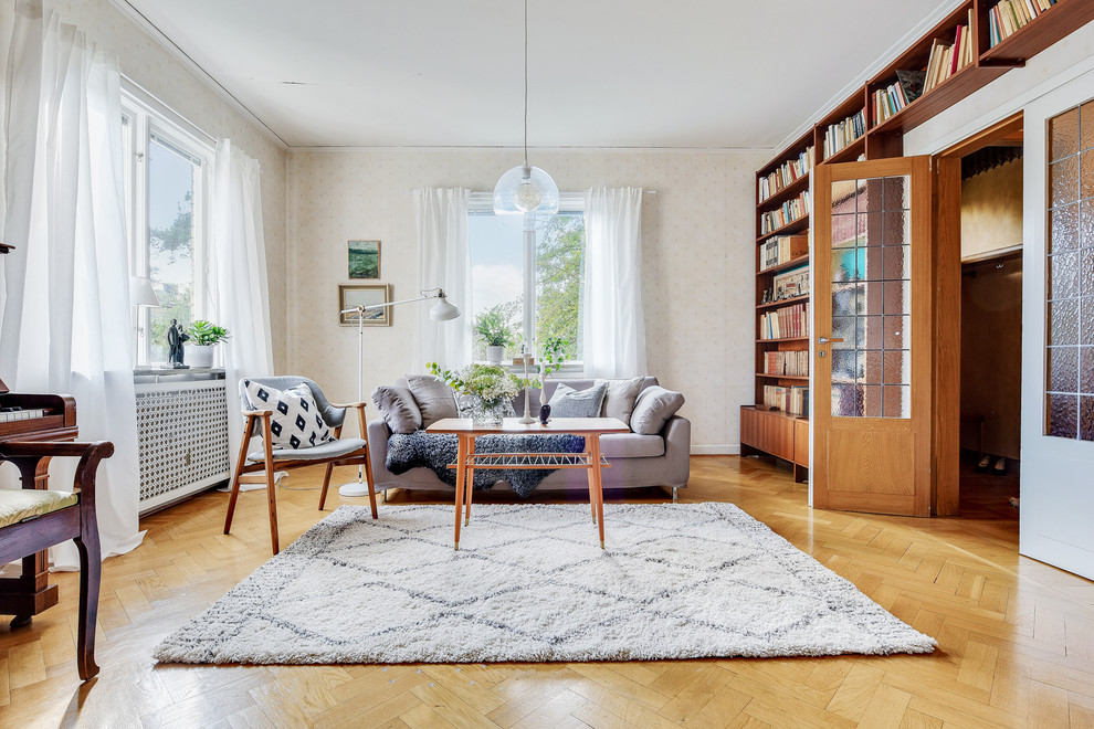 This is an example of a scandinavian enclosed living room in Stockholm with a library, beige walls, medium hardwood floors and brown floor.