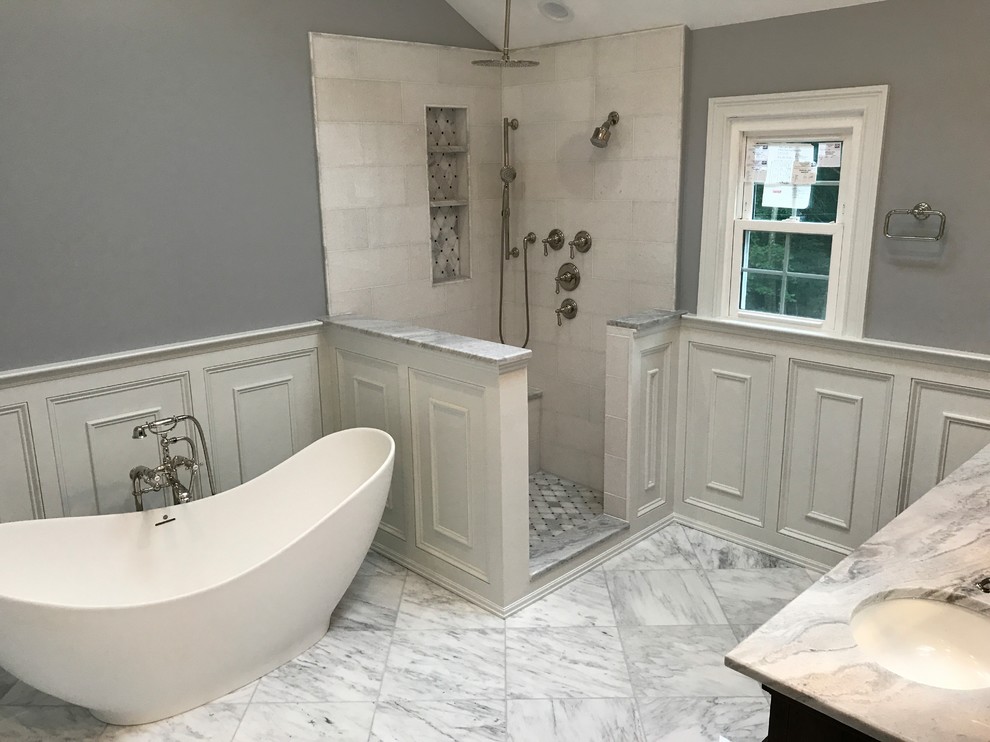 Inspiration for a mid-sized traditional master bathroom in Other with recessed-panel cabinets, dark wood cabinets, a freestanding tub, a corner shower, beige tile, ceramic tile, grey walls, marble floors, an undermount sink, marble benchtops, white floor and an open shower.