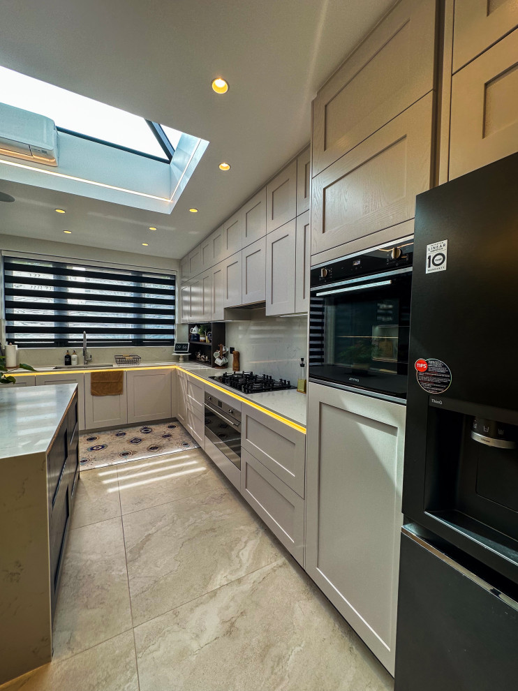 Design ideas for a large traditional l-shaped kitchen/diner in London with a built-in sink, shaker cabinets, blue cabinets, quartz worktops, white splashback, engineered quartz splashback, integrated appliances, porcelain flooring, an island, beige floors, white worktops and feature lighting.