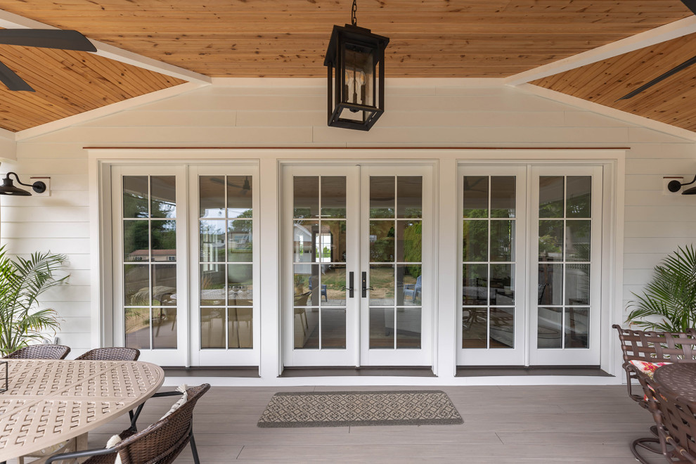 Cette image montre un grand porche d'entrée de maison arrière marin avec une terrasse en bois et une extension de toiture.
