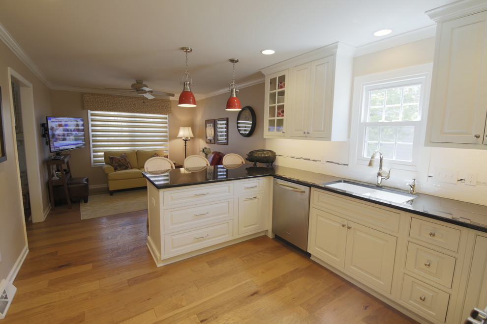 Inspiration for a transitional u-shaped medium tone wood floor kitchen remodel in Chicago with an undermount sink, raised-panel cabinets, white cabinets, granite countertops, white backsplash, subway tile backsplash and stainless steel appliances