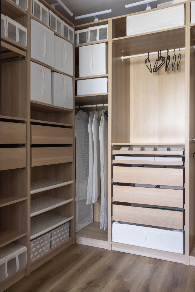 Mid-sized contemporary gender-neutral walk-in wardrobe in Saint Petersburg with light wood cabinets, vinyl floors and brown floor.