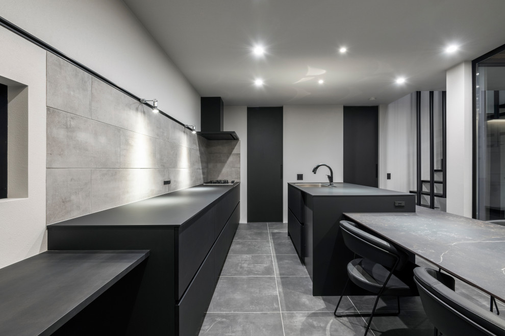 Inspiration for a mid-sized contemporary galley eat-in kitchen in Tokyo Suburbs with ceramic floors, black floor, wallpaper, an undermount sink, flat-panel cabinets, black cabinets, concrete benchtops, grey splashback, ceramic splashback, black appliances, with island and black benchtop.