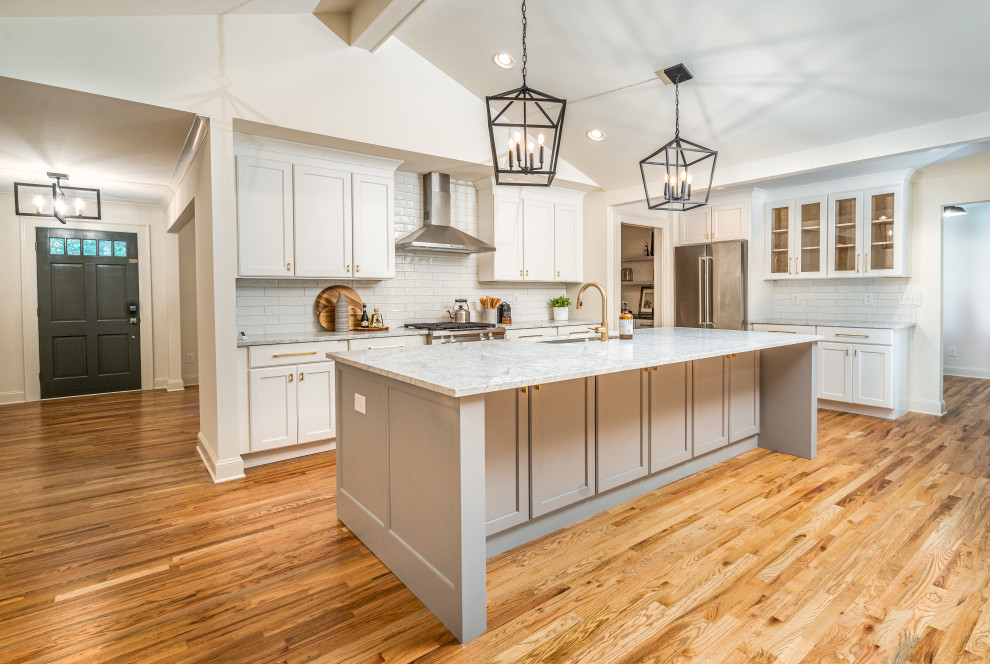 This is an example of a transitional l-shaped open plan kitchen in Atlanta with white cabinets and with island.