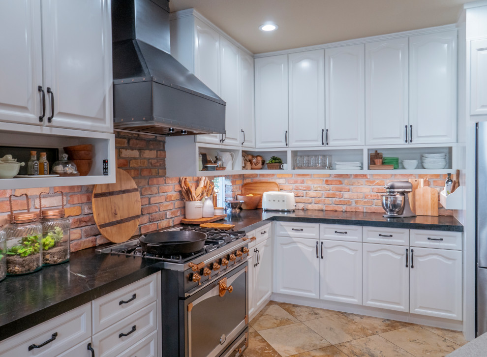 Design ideas for a mid-sized mediterranean single-wall eat-in kitchen in Sacramento with shaker cabinets, white cabinets, soapstone benchtops, red splashback, brick splashback, stainless steel appliances, with island and black benchtop.