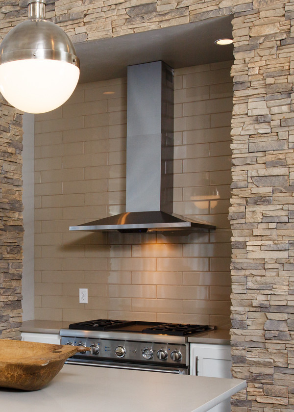 Example of a transitional kitchen design with recessed-panel cabinets, white cabinets, limestone countertops, beige backsplash, subway tile backsplash, stainless steel appliances and an island