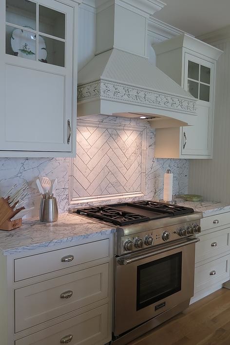 Inspiration for a mid-sized timeless l-shaped light wood floor eat-in kitchen remodel with an undermount sink, shaker cabinets, white cabinets, white backsplash, stone tile backsplash, stainless steel appliances, an island and marble countertops