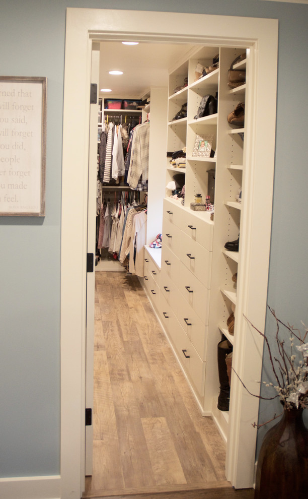 Small country gender-neutral walk-in wardrobe in Seattle with flat-panel cabinets, white cabinets, vinyl floors and brown floor.