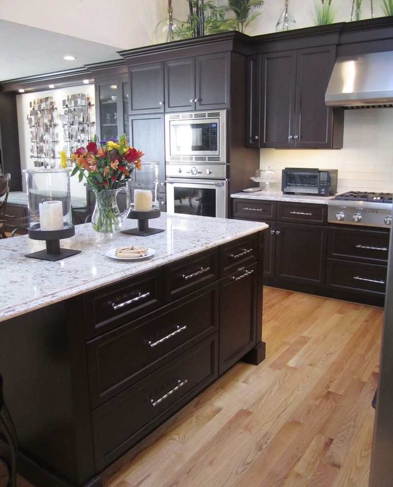 Large transitional l-shaped light wood floor eat-in kitchen photo with shaker cabinets, black cabinets, marble countertops, white backsplash, subway tile backsplash, stainless steel appliances and an island