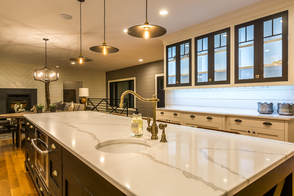 Eat-in kitchen - large transitional galley medium tone wood floor eat-in kitchen idea in Cedar Rapids with a farmhouse sink, shaker cabinets, beige cabinets, marble countertops, white backsplash, subway tile backsplash, stainless steel appliances and an island