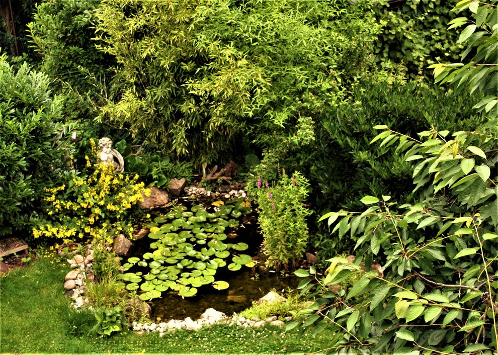 Kleiner, Halbschattiger Landhaus Gartenteich im Sommer, neben dem Haus mit Natursteinplatten in Sonstige