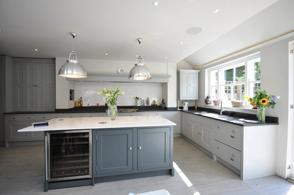 Large contemporary l-shaped eat-in kitchen in London with an undermount sink, beaded inset cabinets, grey cabinets, granite benchtops, white splashback, subway tile splashback, panelled appliances, porcelain floors, with island, grey floor, grey benchtop and vaulted.