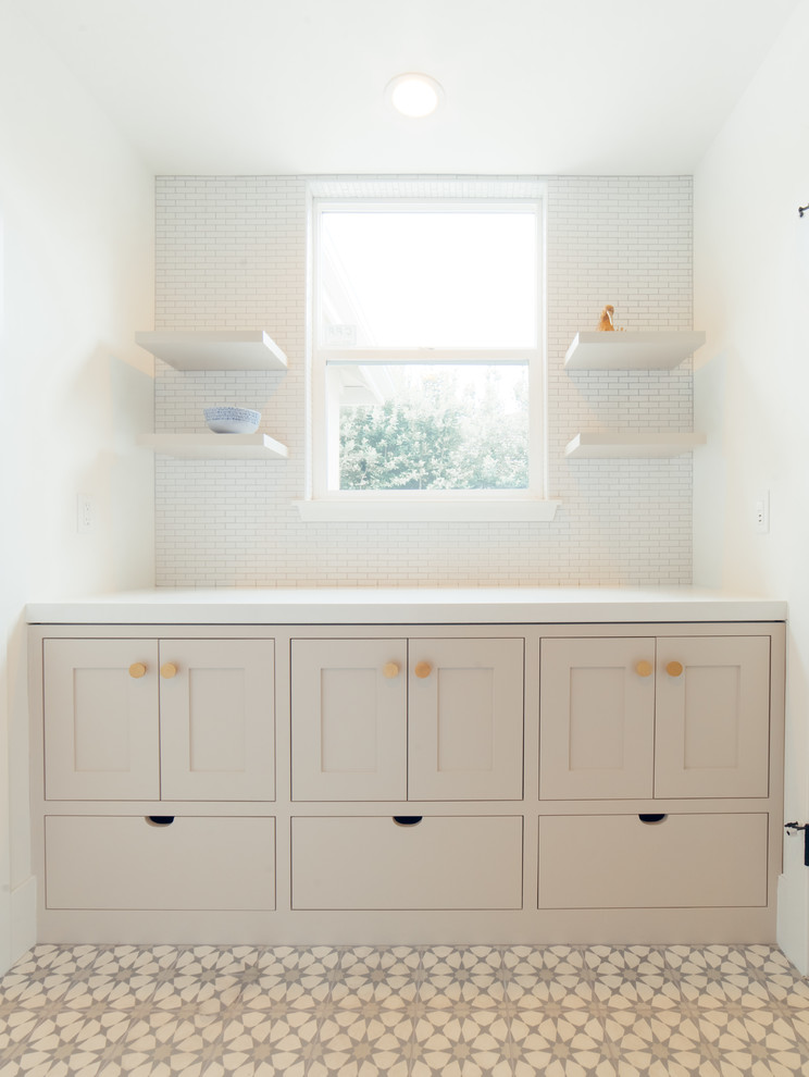 Inspiration for a large contemporary single-wall dedicated laundry room in Sacramento with shaker cabinets, beige cabinets, solid surface benchtops, white walls, ceramic floors, multi-coloured floor and white benchtop.