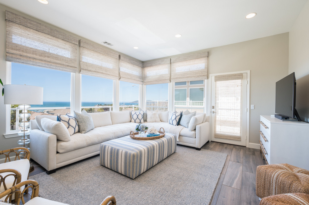 Inspiration for a mid-sized beach style open concept living room in San Luis Obispo with laminate floors, grey walls, a freestanding tv and brown floor.