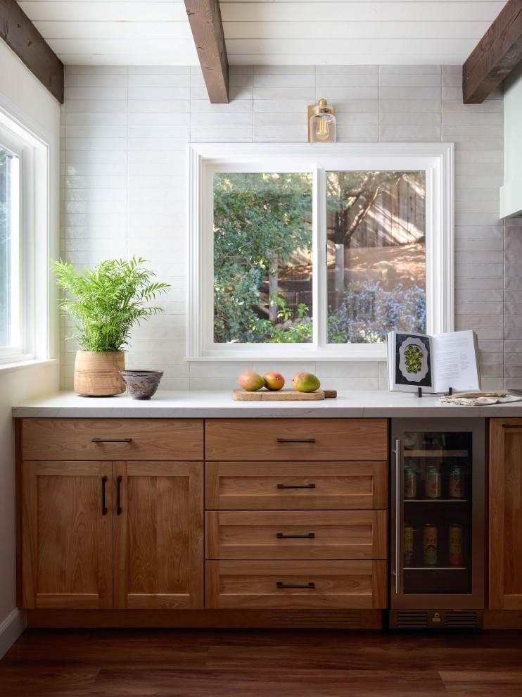 Eat-in kitchen - mid-sized transitional l-shaped medium tone wood floor, brown floor and exposed beam eat-in kitchen idea with a single-bowl sink, shaker cabinets, medium tone wood cabinets, quartz countertops, white backsplash, subway tile backsplash, stainless steel appliances, an island and white countertops