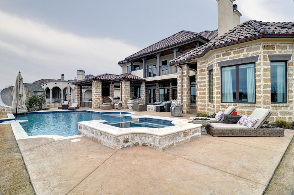 Large transitional backyard custom-shaped natural pool in Dallas with a water slide and stamped concrete.