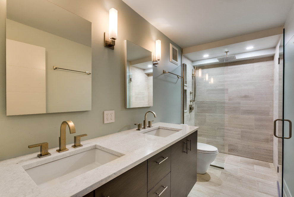 Inspiration for a mid-sized modern master bathroom in Chicago with flat-panel cabinets, dark wood cabinets, a curbless shower, beige tile, ceramic tile, grey walls, laminate floors, an undermount sink, marble benchtops, beige floor, a hinged shower door and a two-piece toilet.