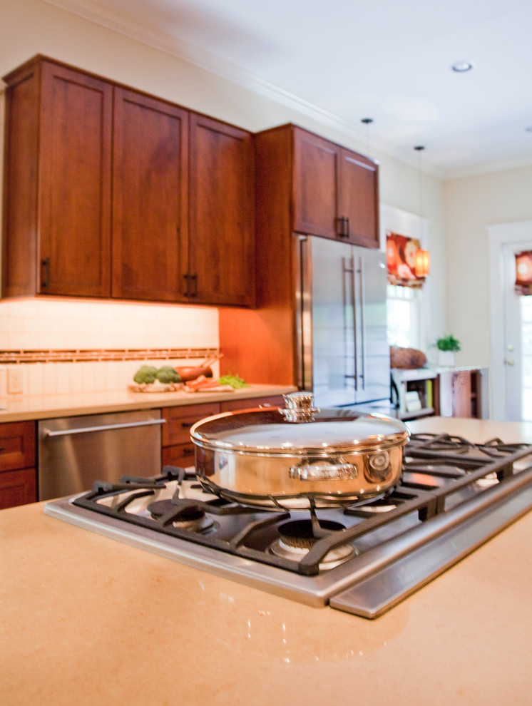 Mid-sized arts and crafts eat-in kitchen in New Orleans with beaded inset cabinets, medium wood cabinets, orange splashback, mosaic tile splashback, stainless steel appliances, with island and beige benchtop.