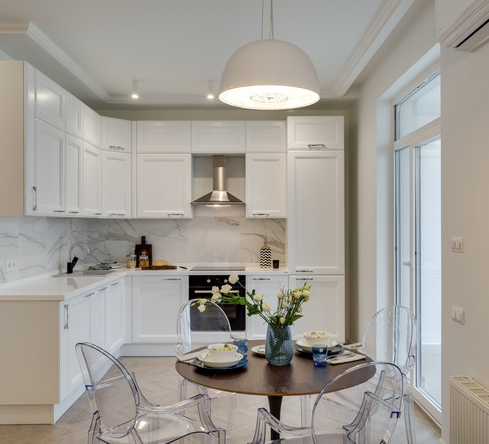 Photo of a transitional l-shaped eat-in kitchen in Moscow with a drop-in sink, recessed-panel cabinets, white cabinets, white splashback, black appliances, no island, beige floor and marble splashback.