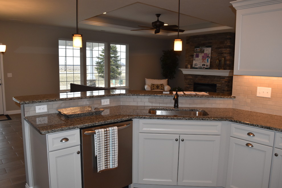 Enclosed kitchen - mid-sized transitional u-shaped porcelain tile enclosed kitchen idea with an undermount sink, recessed-panel cabinets, beige cabinets, granite countertops, beige backsplash, subway tile backsplash, stainless steel appliances and a peninsula