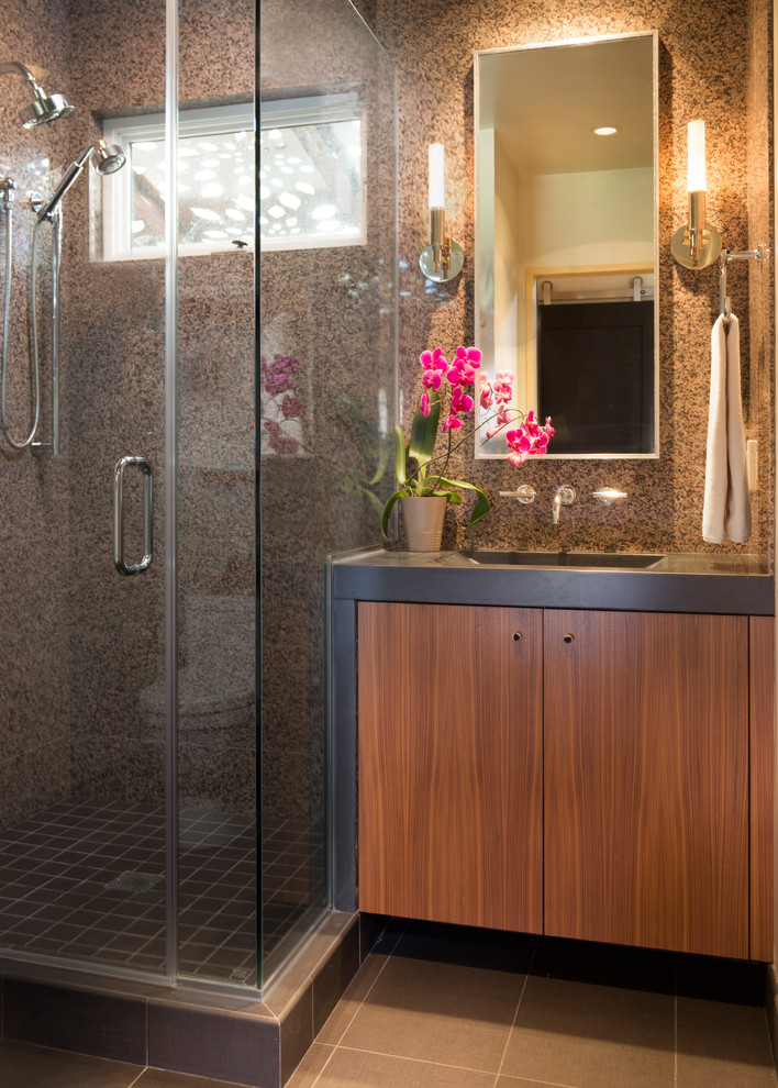 This is an example of a mid-sized transitional 3/4 bathroom in Cleveland with flat-panel cabinets, medium wood cabinets, a corner shower, gray tile, stone tile, ceramic floors, an integrated sink, concrete benchtops, beige walls, grey floor and a hinged shower door.
