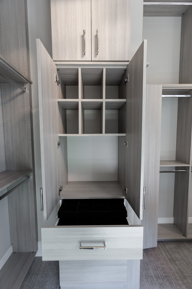This is an example of a large walk-in wardrobe in Minneapolis with flat-panel cabinets, grey cabinets, carpet and grey floor.