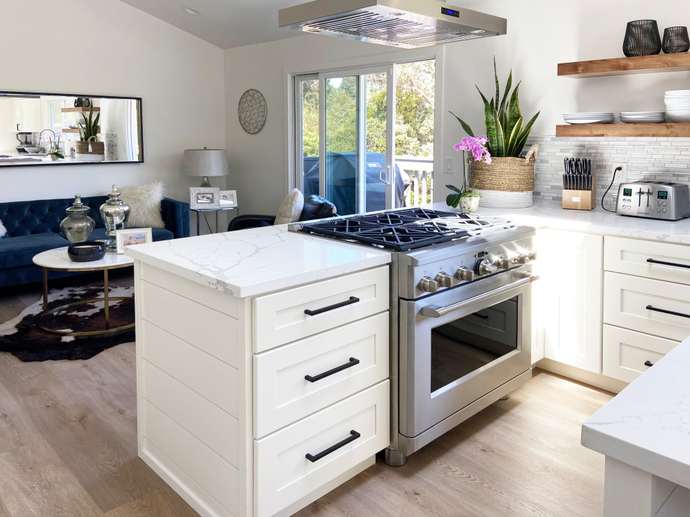 Inspiration for a mid-sized transitional l-shaped vinyl floor, brown floor and vaulted ceiling eat-in kitchen remodel with an undermount sink, shaker cabinets, white cabinets, quartz countertops, multicolored backsplash, mosaic tile backsplash, stainless steel appliances, an island and white countertops