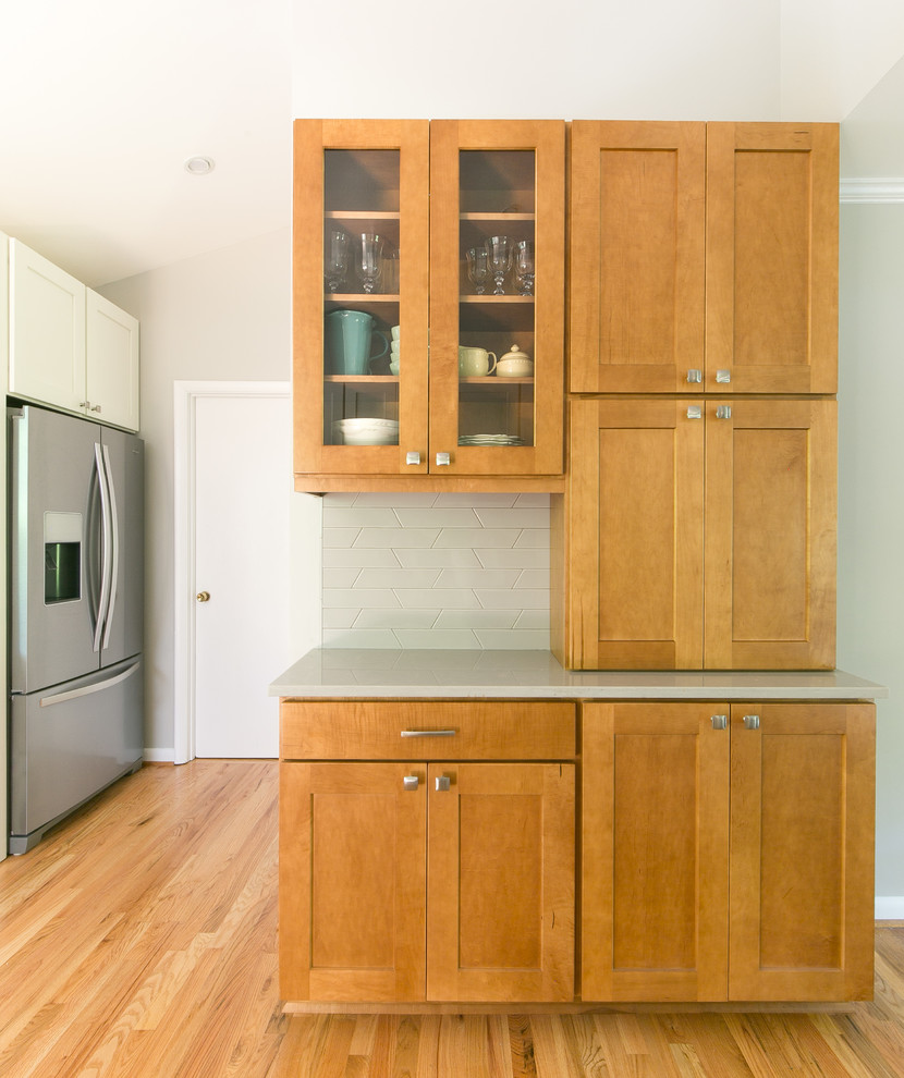 Design ideas for a mid-sized midcentury u-shaped eat-in kitchen in Atlanta with shaker cabinets, white cabinets, quartz benchtops, grey splashback, ceramic splashback, stainless steel appliances, light hardwood floors, a peninsula, brown floor, grey benchtop and a double-bowl sink.