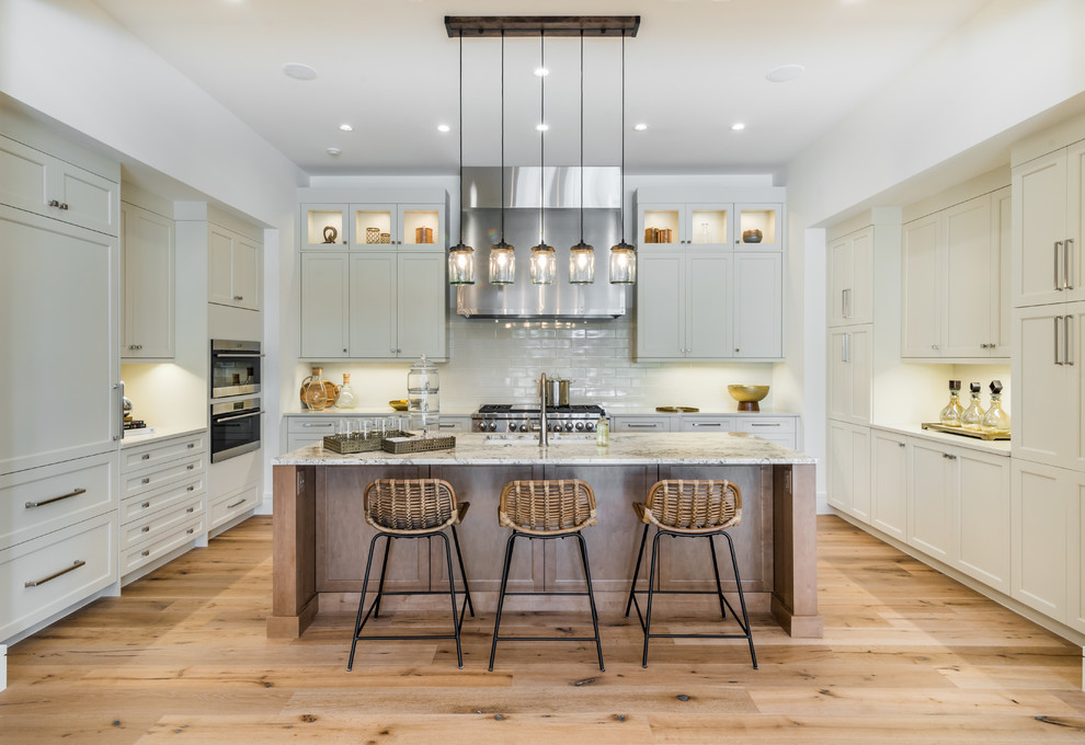 Inspiration for a transitional u-shaped kitchen in Miami with shaker cabinets, beige cabinets, stainless steel appliances, medium hardwood floors, with island, brown floor and beige benchtop.