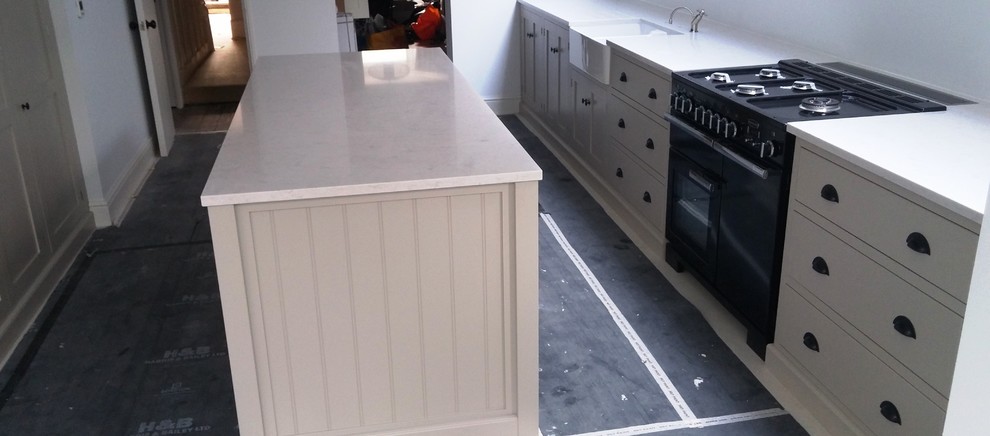Large traditional galley kitchen in London with a farmhouse sink, quartzite benchtops, white splashback and with island.