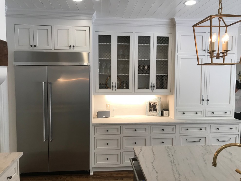 Large transitional u-shaped dark wood floor and brown floor eat-in kitchen photo with an undermount sink, recessed-panel cabinets, white cabinets, marble countertops, white backsplash, subway tile backsplash, stainless steel appliances, an island and white countertops