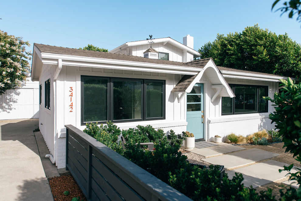 Photo of a small beach style two-storey white house exterior in Orange County with wood siding, a gable roof and a shingle roof.