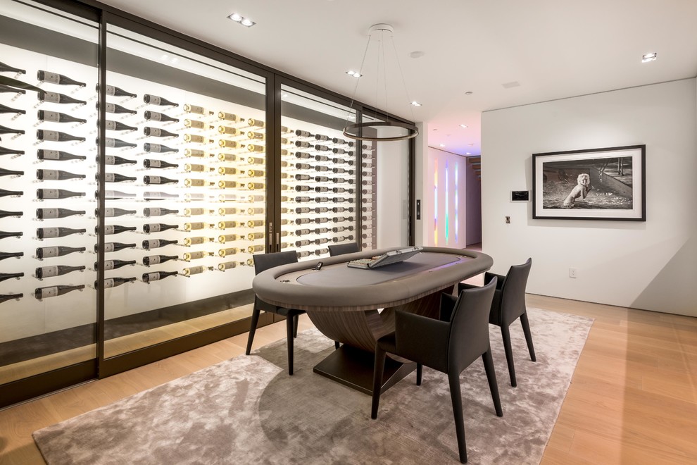 Inspiration for a large modern wine cellar in Los Angeles with light hardwood floors, display racks and beige floor.
