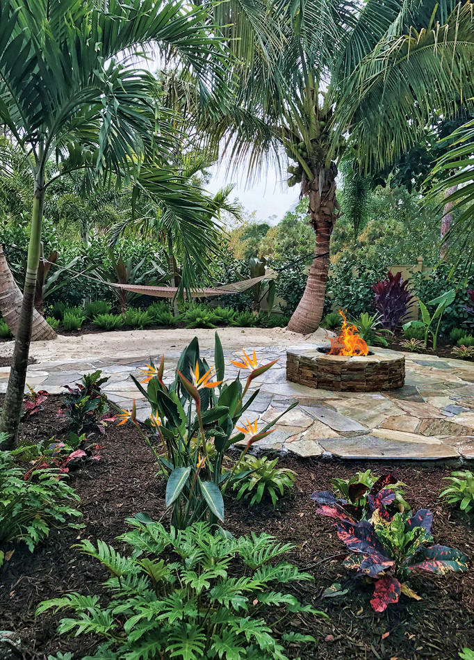 Inspiration for an expansive tropical backyard patio in Miami with a fire feature and natural stone pavers.