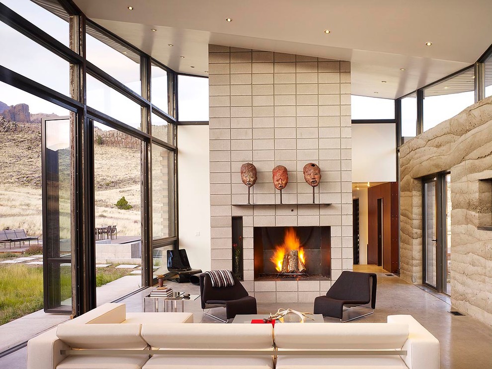 Design ideas for a large contemporary open concept living room in Other with concrete floors, a standard fireplace, beige walls, a concrete fireplace surround and no tv.