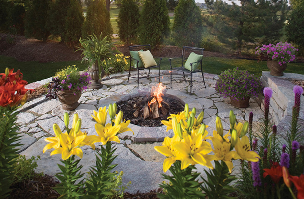 Photo of a traditional backyard patio in Milwaukee with a fire feature, natural stone pavers and no cover.