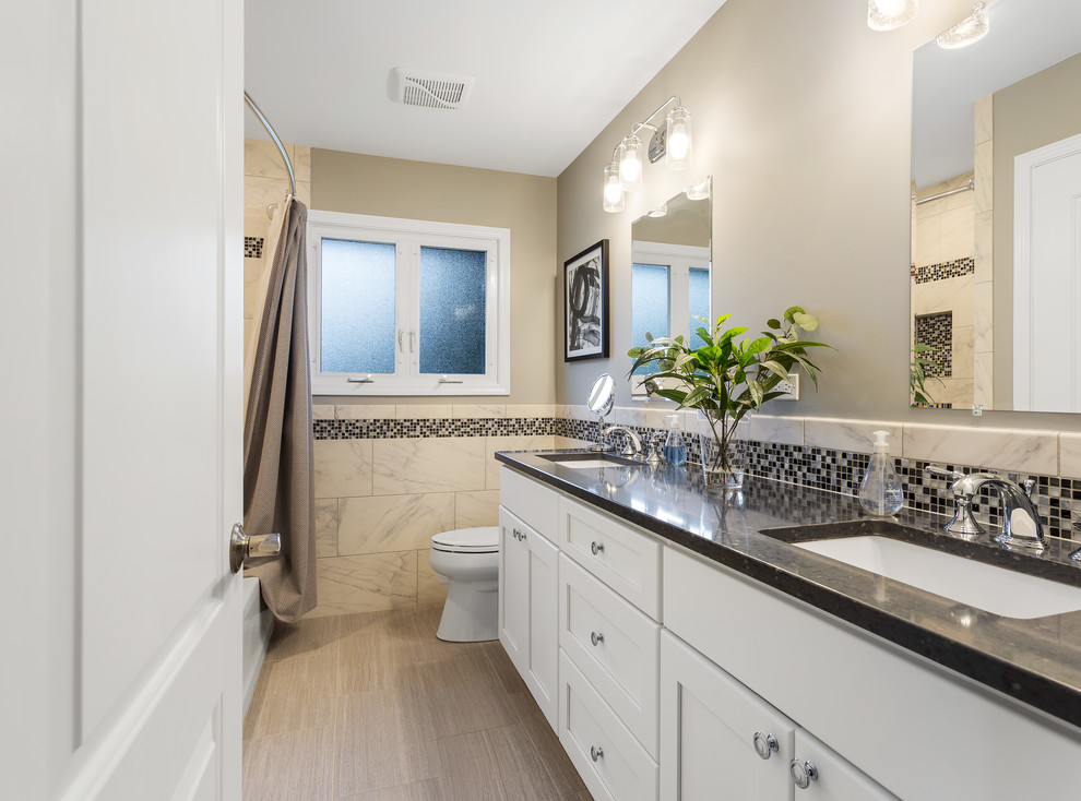 Inspiration for a mid-sized contemporary 3/4 bathroom in Chicago with shaker cabinets, white cabinets, an alcove tub, a shower/bathtub combo, a two-piece toilet, beige tile, ceramic tile, beige walls, ceramic floors, an undermount sink, quartzite benchtops, beige floor, a shower curtain and black benchtops.