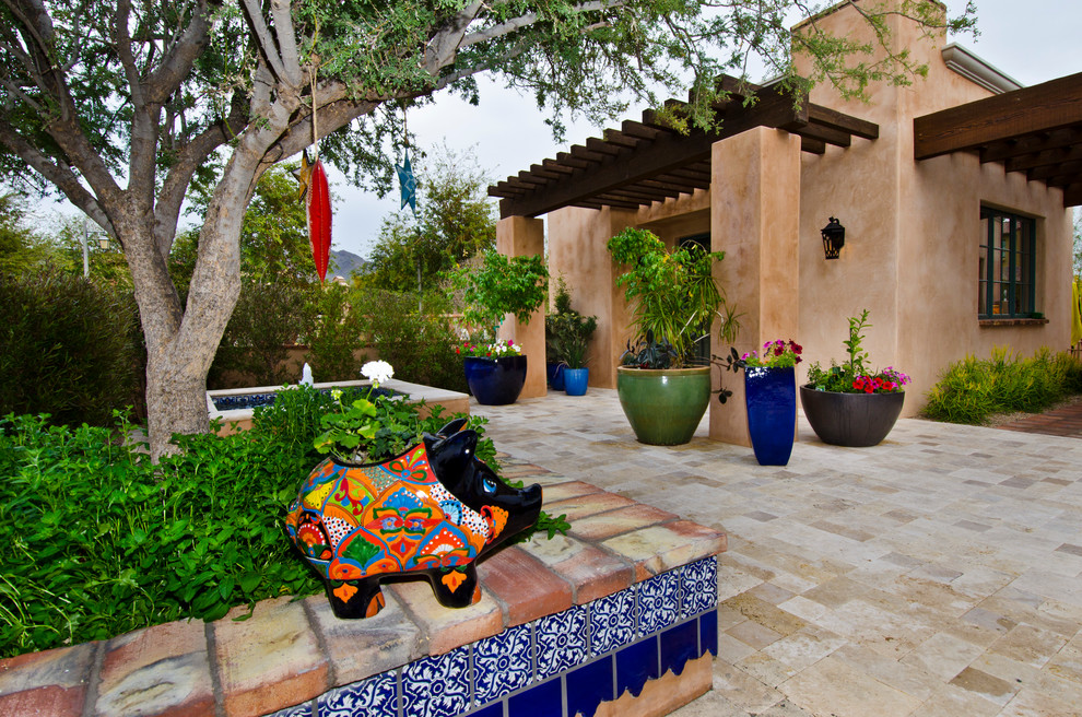 This is an example of a mid-sized front yard patio in Phoenix with a water feature, natural stone pavers and a pergola.